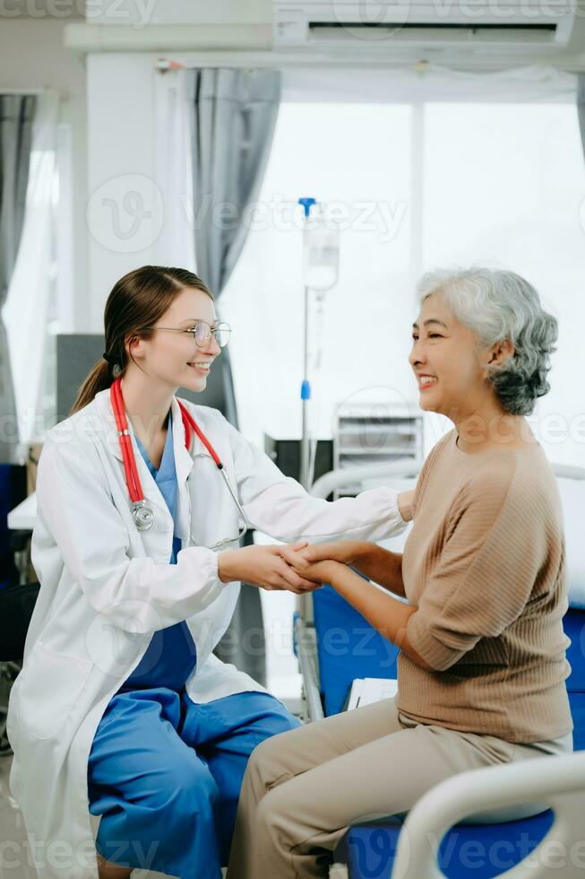 Friendly Female Head Nurse Making Rounds does Checkup on Patient Resting in Bed. She Checks tablet while Man Fully Recovering after Successful Surgery in hospital photo