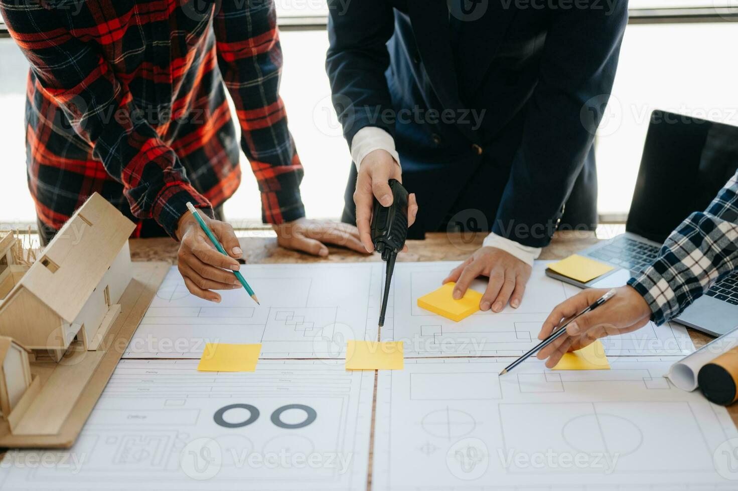 Three colleagues discussing data working and tablet, laptop with on on architectural project at construction site at desk in office photo
