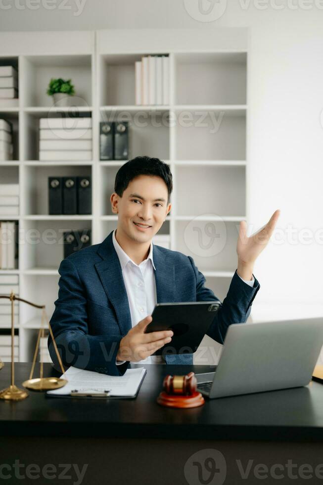 Attractive young lawyer in office Business man and lawyers discussing contract papers laptop and tablet with brass scale on  desk in modern office. Law, legal services, advice, photo