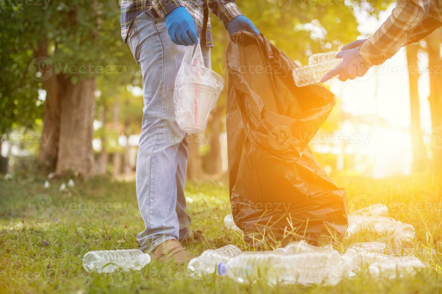 men collect plastic bottles on lawns and walkways in park and put them in bags to help keep them clean They can also collect plastic bottles for recycling. reducing environmental problems by recycling photo