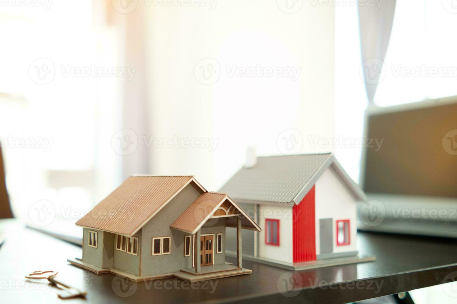 real estate agent places miniature model home on desk inside real estate sales office to allow customers to use  model home as lease option. concept of buying a house from trusted real estate agent photo
