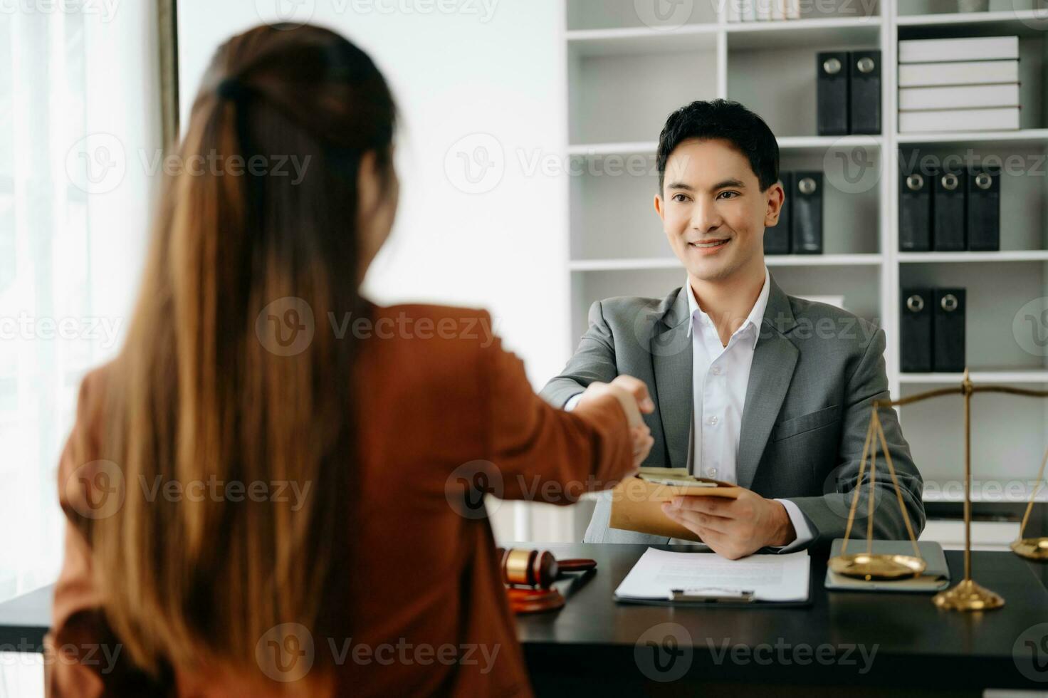 Man lawyer hand and women client shaking hand collaborate on working agreements with contract documents at the office. photo