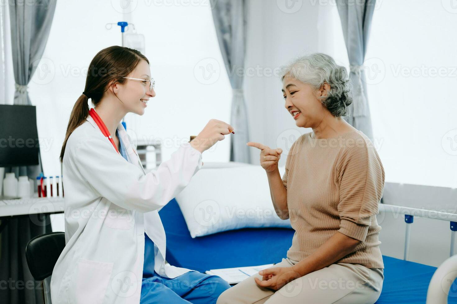 Friendly Female Head Nurse Making Rounds does Checkup on Patient Resting in Bed. She Checks tablet while Man Fully Recovering after Successful Surgery in hospital photo