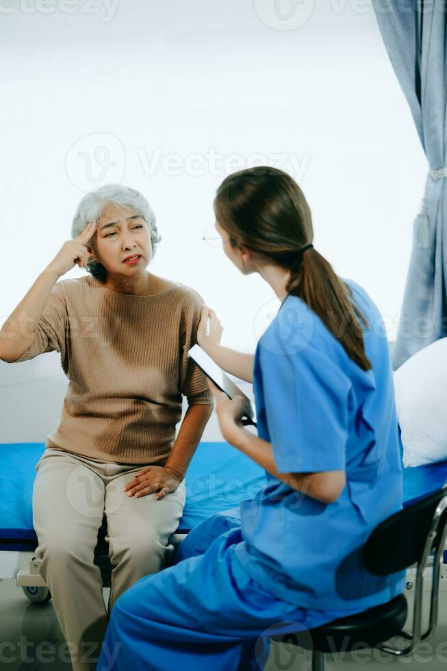 Friendly Female Head Nurse Making Rounds does Checkup on Patient Resting in Bed. She Checks tablet while Man Fully Recovering after Successful Surgery in hospital photo