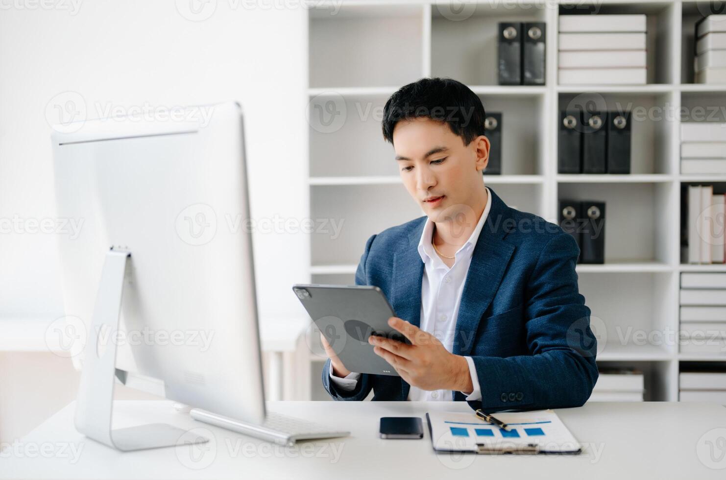 Business man using tablet and laptop for doing math finance on an office desk, tax, report, accounting, statistics, and analytical research concept in office photo