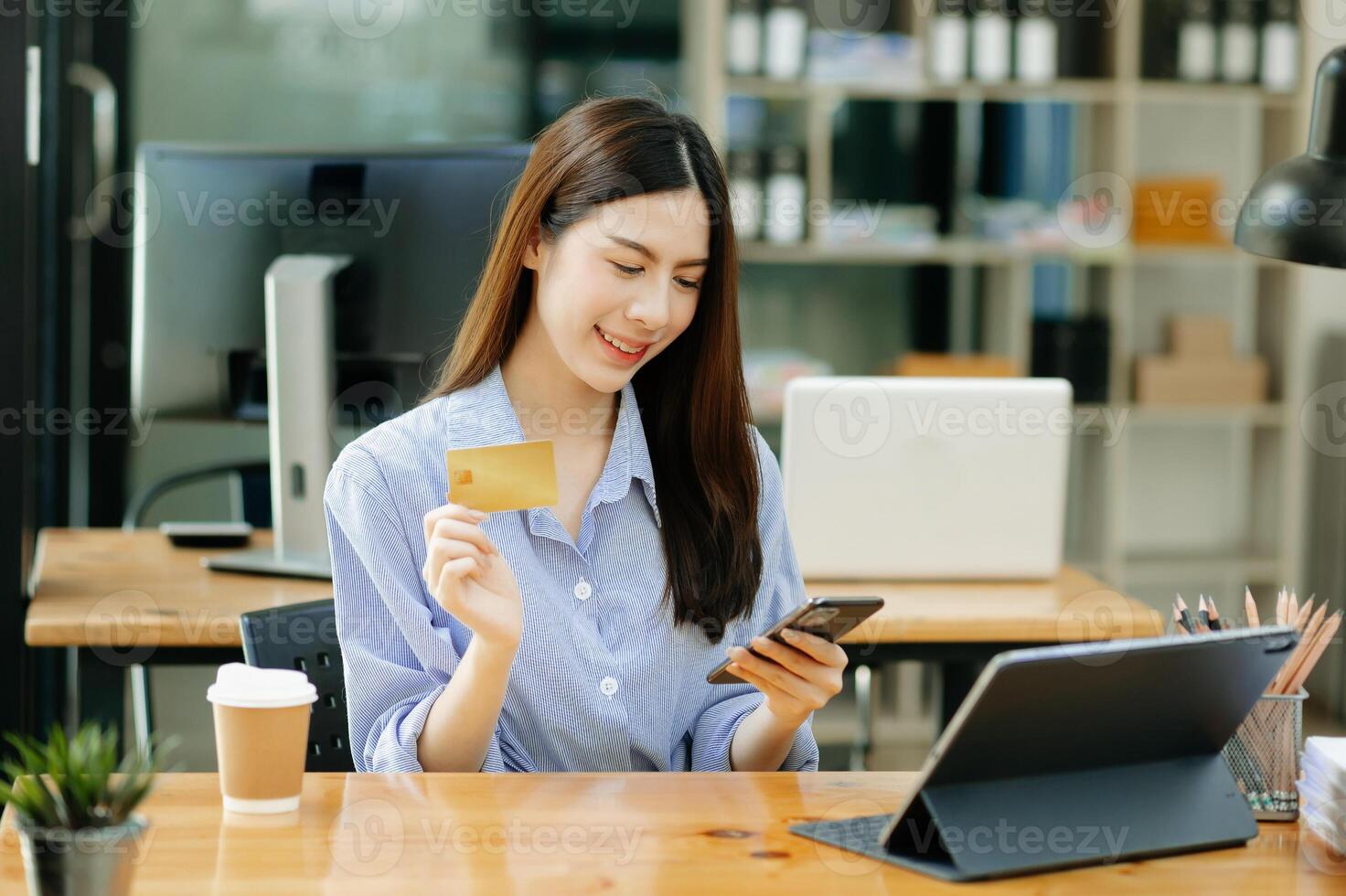 Asian Woman using smart phone for mobile payments online shopping,omni channel,sitting on table,virtual icons graphics interface screen in morning light photo