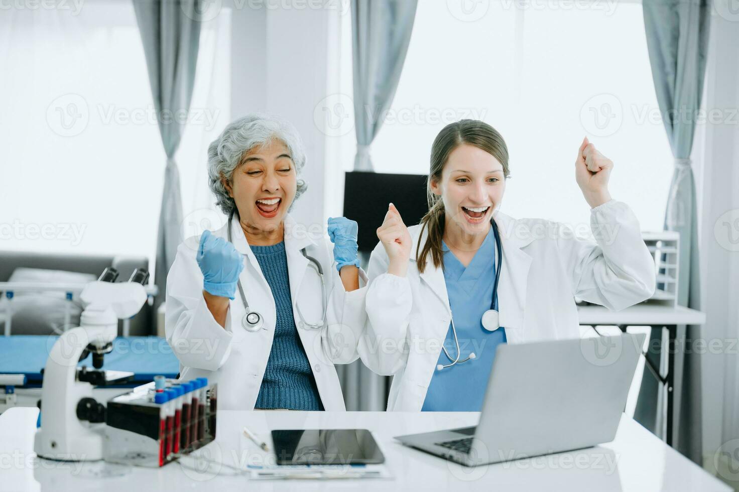 Medical team having a meeting with doctors in white lab coats and surgical scrubs seated at a table discussing a patients working online using computers in the medical industry photo