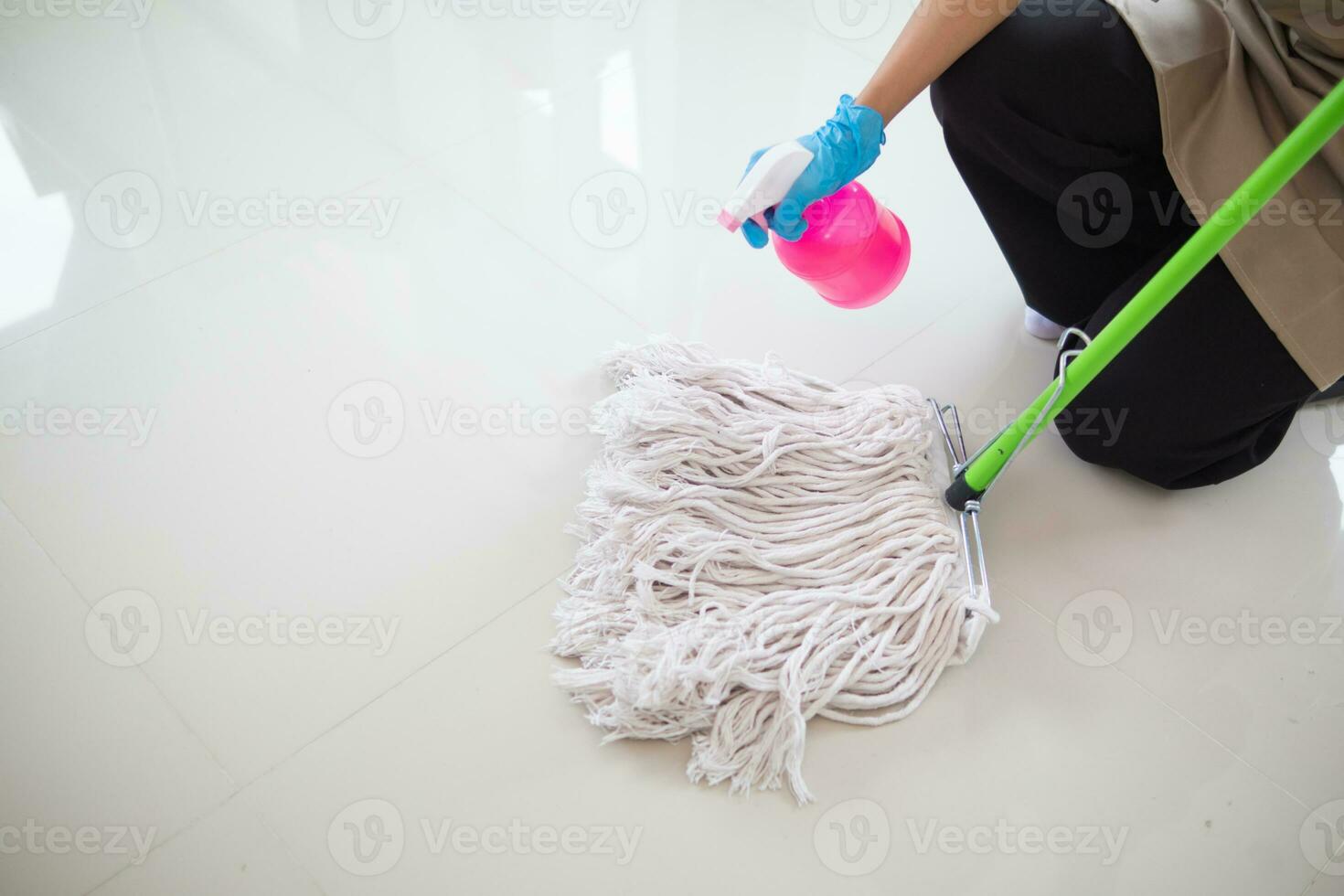 Cleaning staff is wiping cloth with cleaner and disinfectant on the surface of floor to make the floor clean with cleaning products and free from germs clinging to surface of the floor in living room. photo