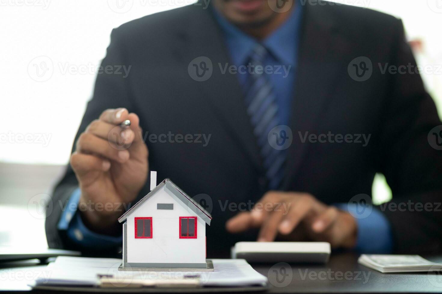 The real estate agent is reviewing the documents and calculating the interest rate to inform the tenant of the monthly installments to be paid before the real estate purchase agreement is finalized. photo