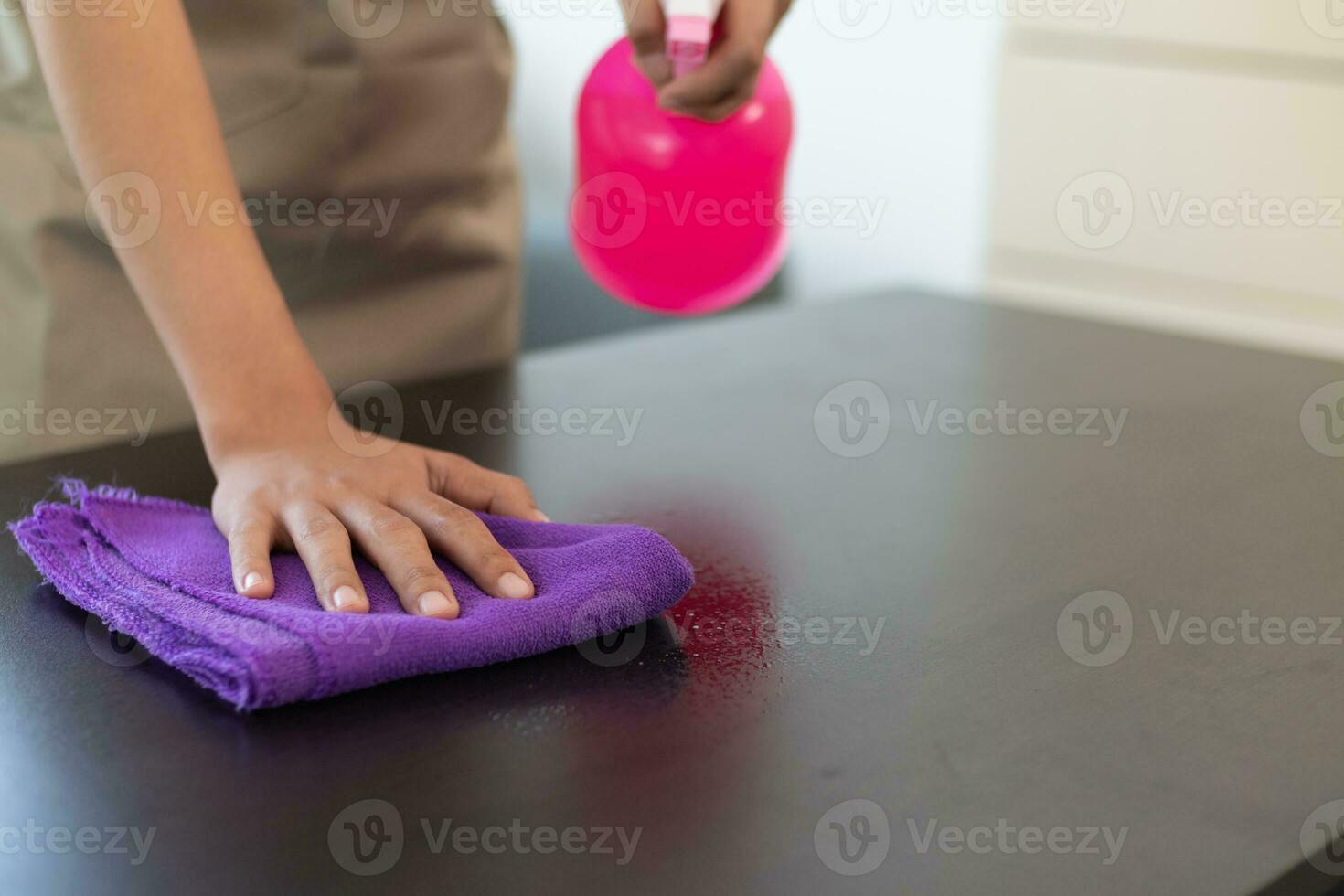 Cleaning staff is wiping cloth with cleaner and disinfectant on the surface of table to make the table clean with cleaning products and free from germs clinging to surface of the table in living room. photo