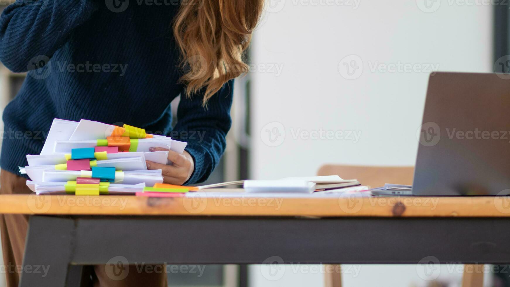 secretary searches through stacked documents on desk in office to find lease within stacked documents just before meeting. concept difficulty in finding hire purchase contract from stacked documents photo