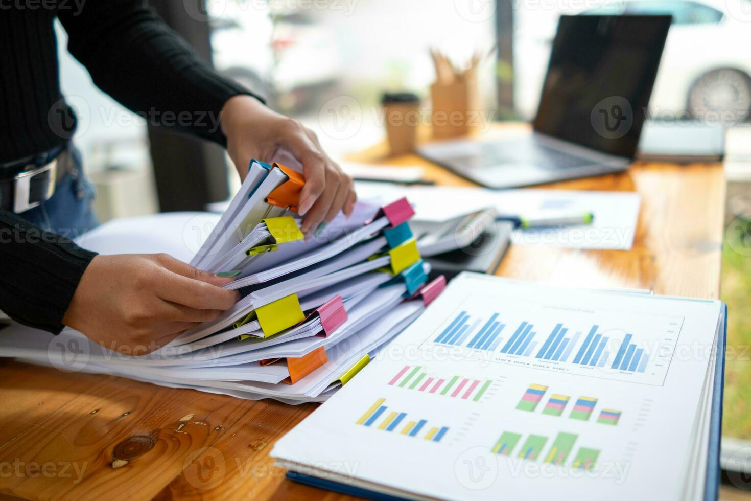 secretary searches through stacked documents on desk in office to find lease within stacked documents just before meeting. concept difficulty in finding hire purchase contract from stacked documents photo