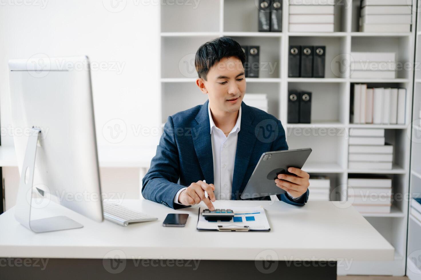 Business man using tablet and laptop for doing math finance on an office desk, tax, report, accounting, statistics, and analytical research concept in office photo