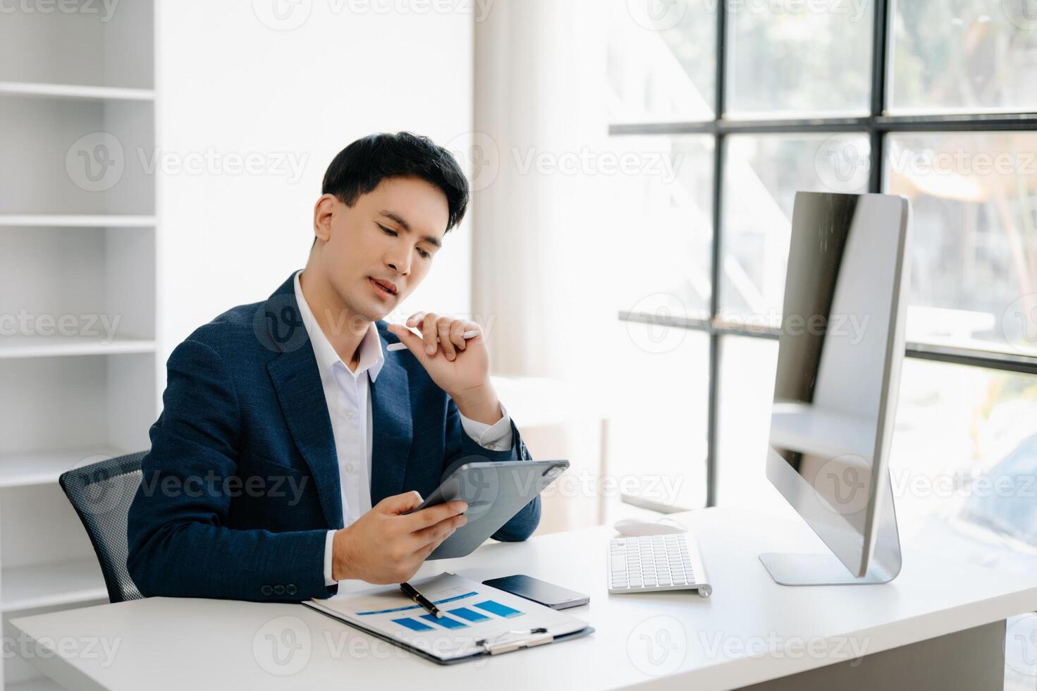 Business man using tablet and laptop for doing math finance on an office desk, tax, report, accounting, statistics, and analytical research concept in office photo