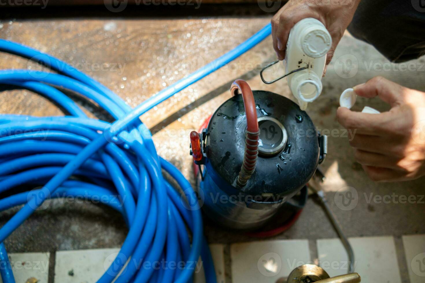 young man chooses to use termite control chemicals that are not toxic to humans mixed with water in tank for spraying to eliminate termites. enabling young man to spray termite repellant by himself photo