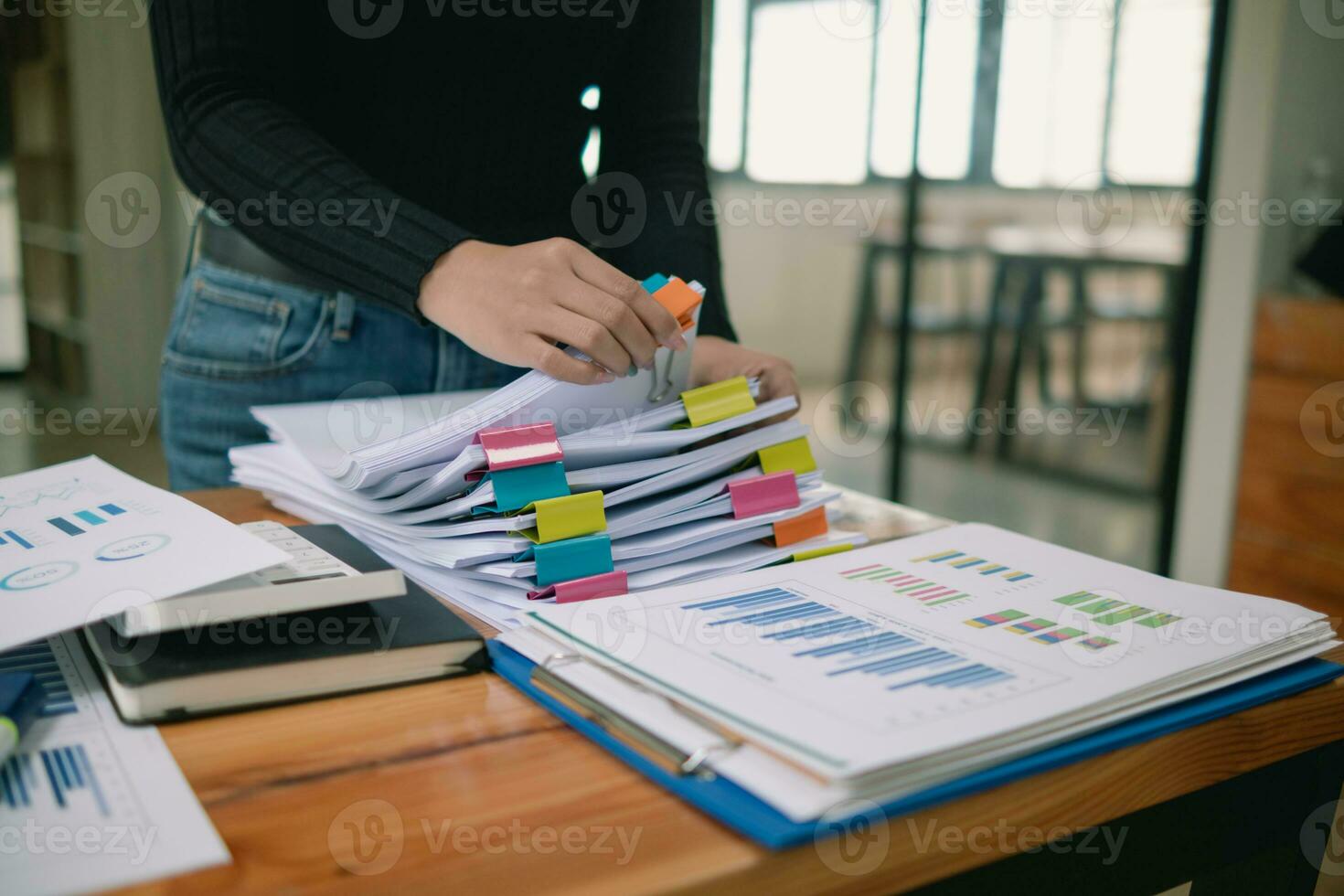 secretary searches through stacked documents on desk in office to find lease within stacked documents just before meeting. concept difficulty in finding hire purchase contract from stacked documents photo