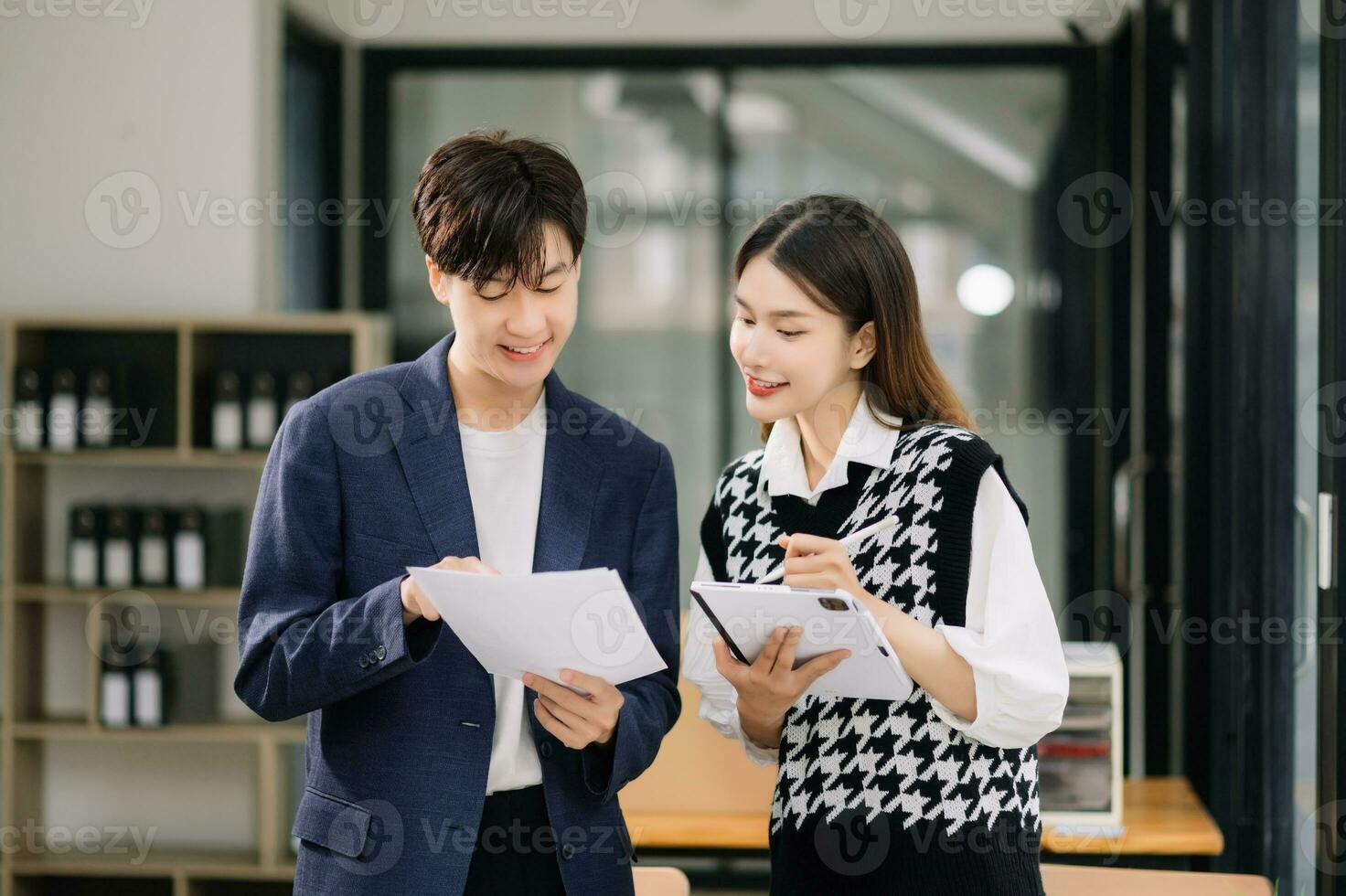 Two Asian business workers talking on the smartphone and using laptop at the modern office. photo