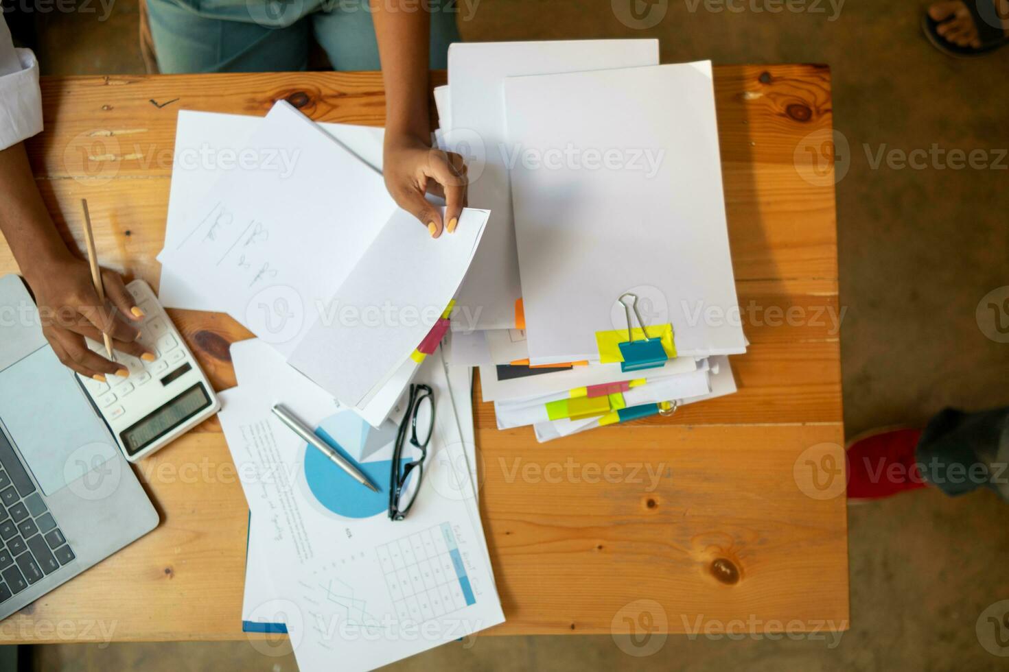 secretary searches through stacked documents on desk in office to find lease within stacked documents just before meeting. concept difficulty in finding hire purchase contract from stacked documents photo