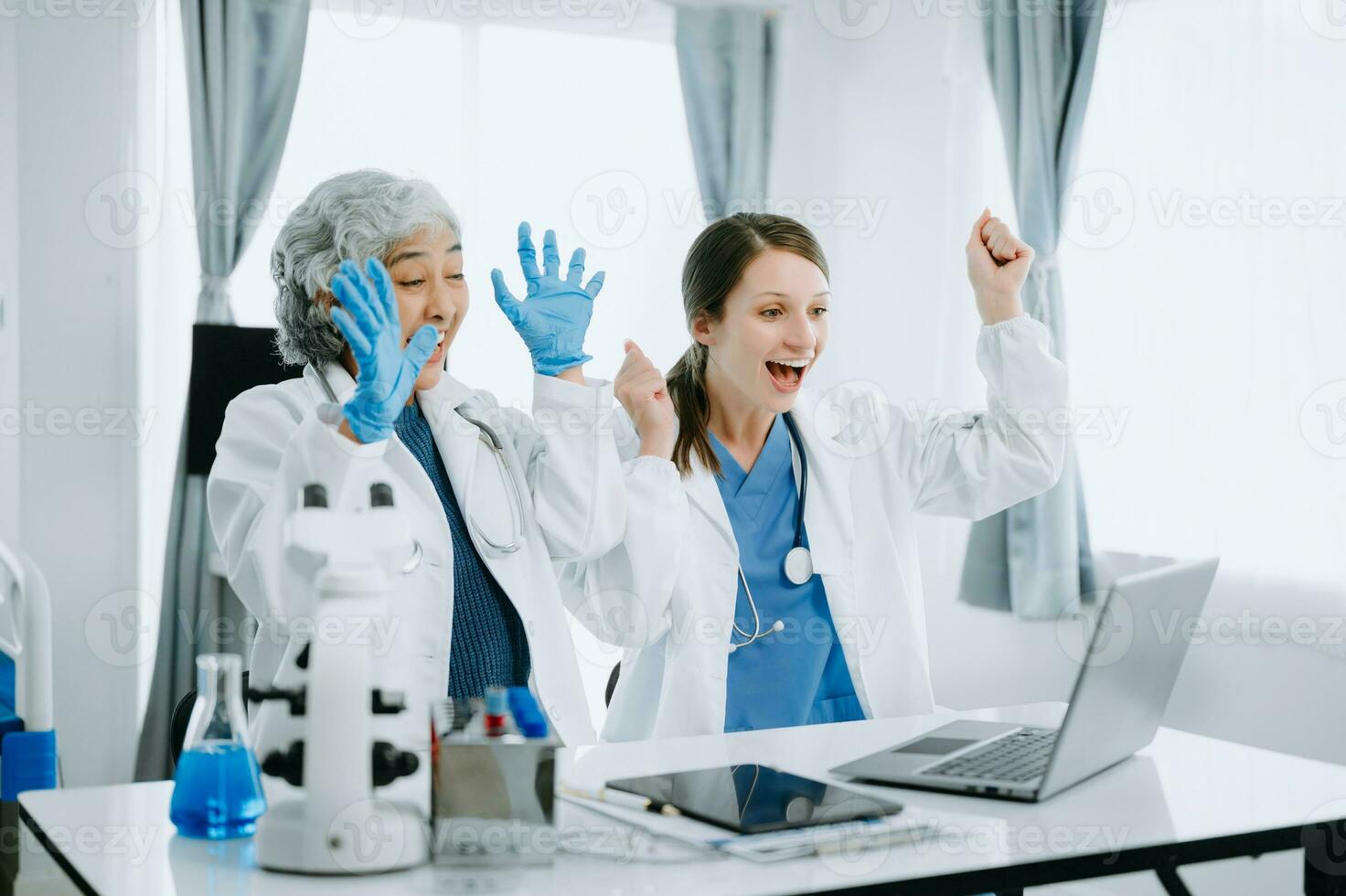 Medical team having a meeting with doctors in white lab coats and surgical scrubs seated at a table discussing a patients working online using computers in the medical industry photo