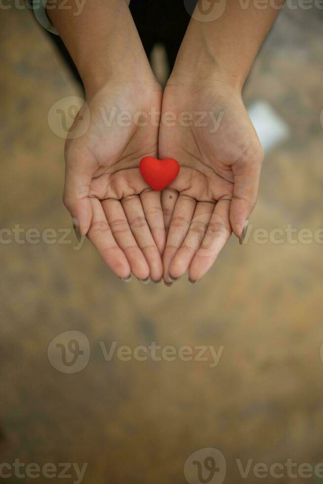 un pequeño rojo corazón simboliza el amar, amabilidad y amistad ese un joven mujer ofertas a alguien. concepto de utilizando corazones como un símbolo de amar, amistad, amabilidad y compasión. foto