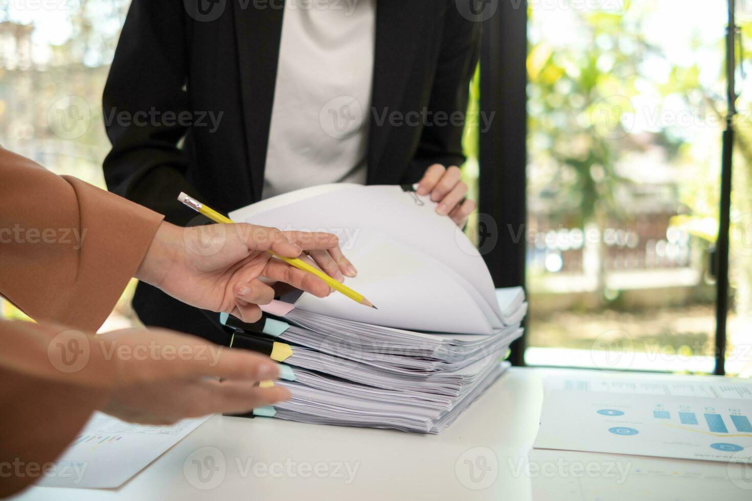 secretary searches through stacked documents on desk in office to find lease within stacked documents just before meeting. concept difficulty in finding hire purchase contract from stacked documents photo