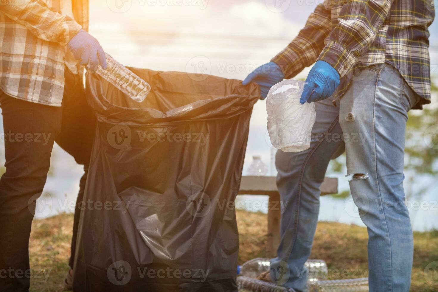 men collect plastic bottles on lawns and walkways in park and put them in bags to help keep them clean They can also collect plastic bottles for recycling. reducing environmental problems by recycling photo