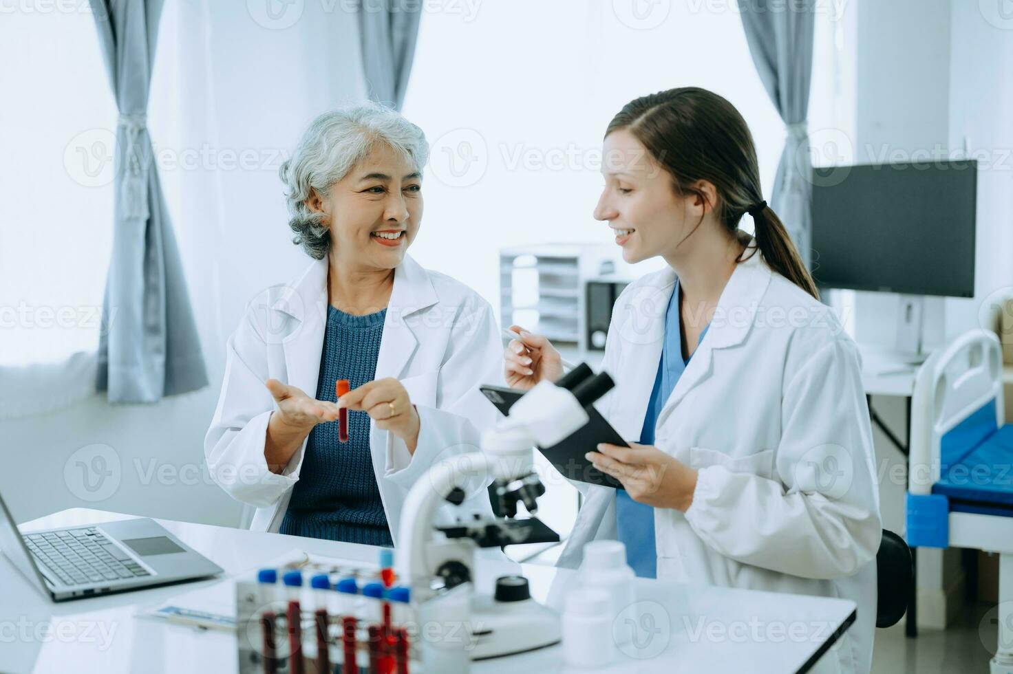 Two scientist or medical technician working, having a medical discuss meeting with an Asian senior female scientist supervisor in the laboratory with online reading, test samples and innovation photo