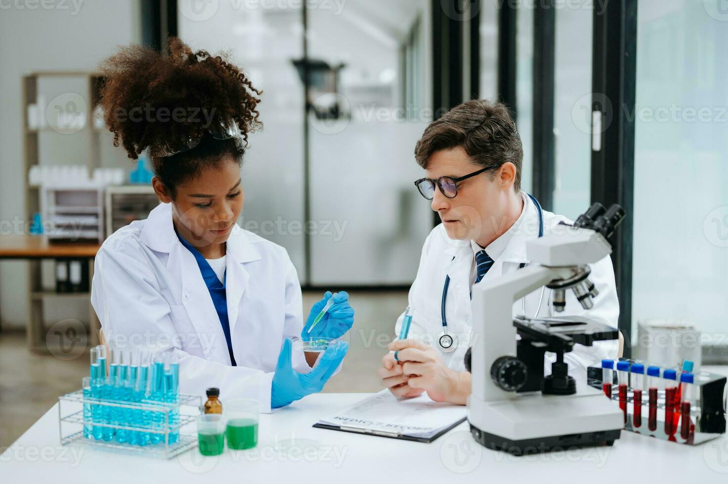 Focused mature male doctor and African female nurse look at tablet and laptop screen discuss anamnesis together. Concentrated diverse medical professionals photo