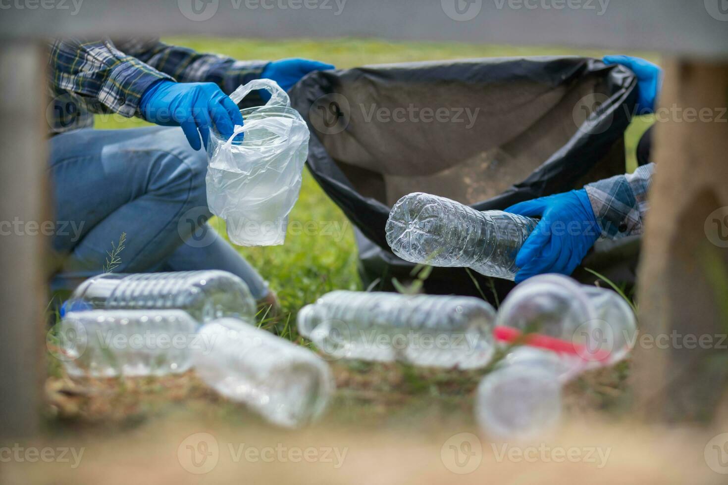 men collect plastic bottles on lawns and walkways in park and put them in bags to help keep them clean They can also collect plastic bottles for recycling. reducing environmental problems by recycling photo