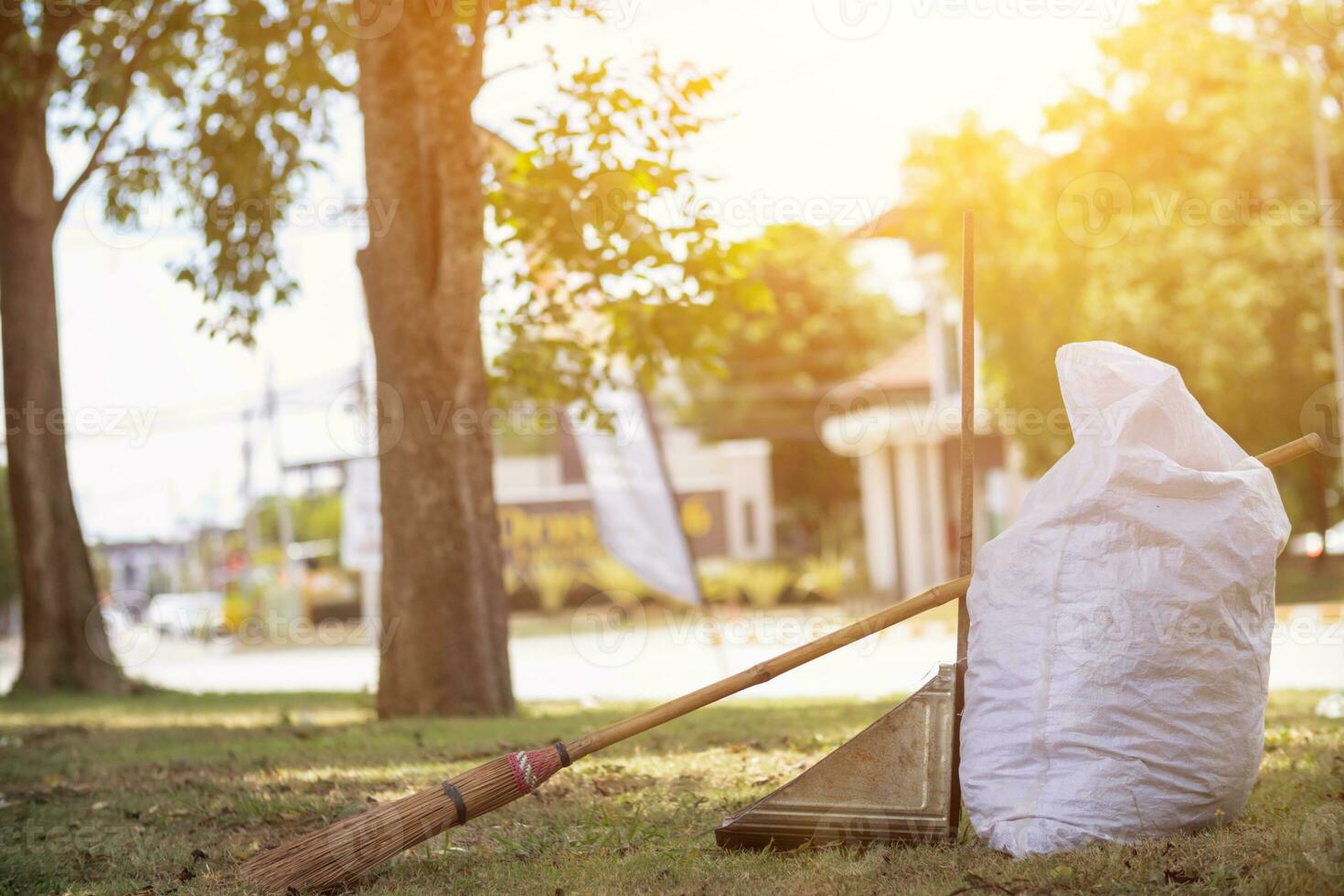 White sacks are used to contain dead leaves that have fallen seasonally in spring as way to clean park and mix  leaves to make compost. coconut broom sits next to powder scoop and sack for dry leaves. photo