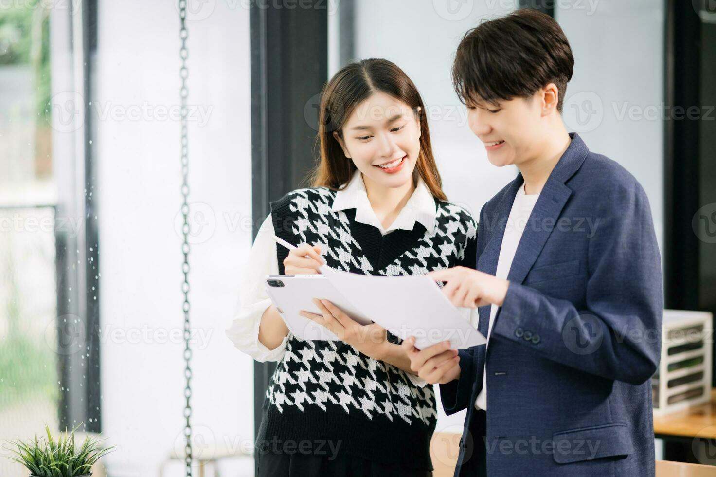 Two Asian business workers talking on the smartphone and using laptop at the modern office. photo