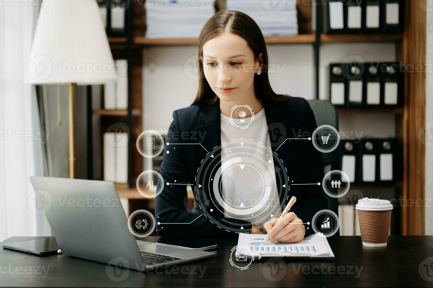Caucasian woman sitting at a desk using a laptop computer and tablet Navigating Finance and Marketing with Technology in office with virtual icon photo