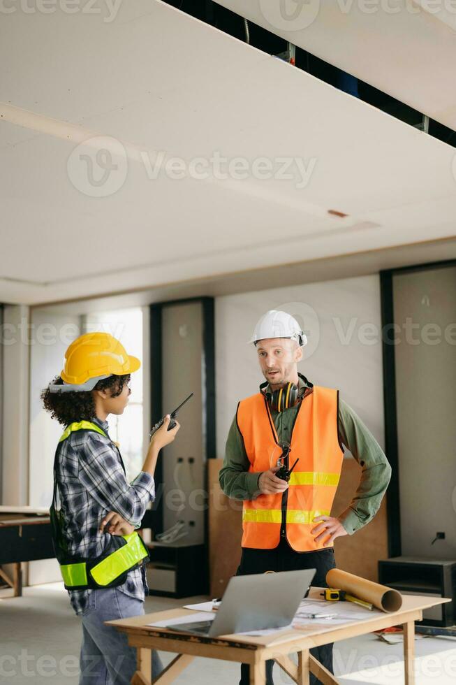 Architect caucasian man and woman working with colleagues mixed race in the construction site. Architecture engineering on big project. Building in construction process interior. photo