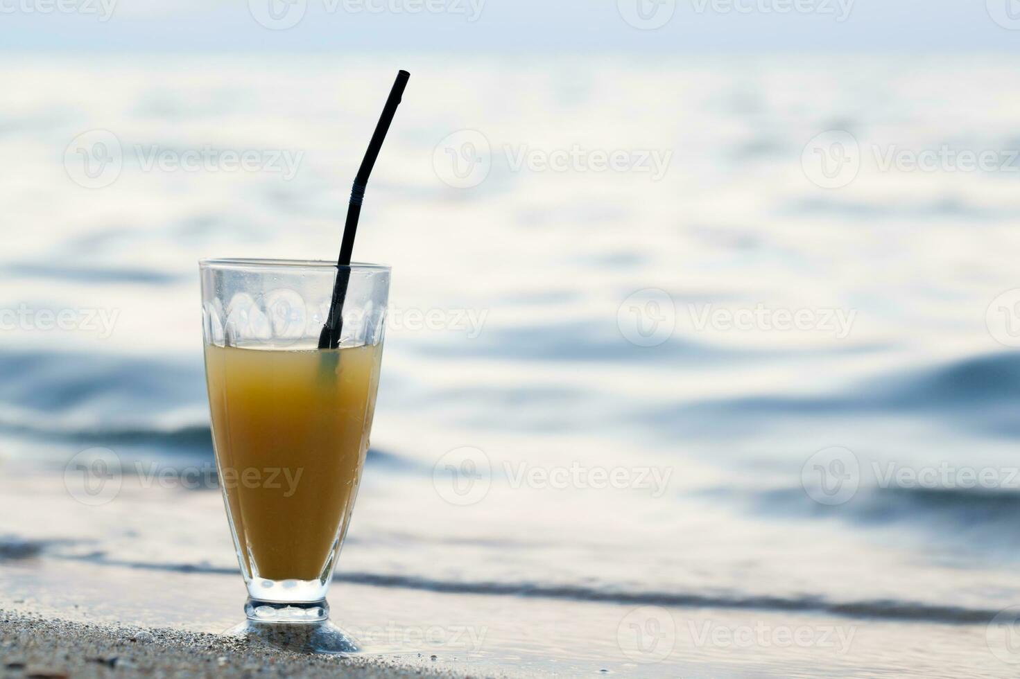 Glass of cocktail on beach near water photo