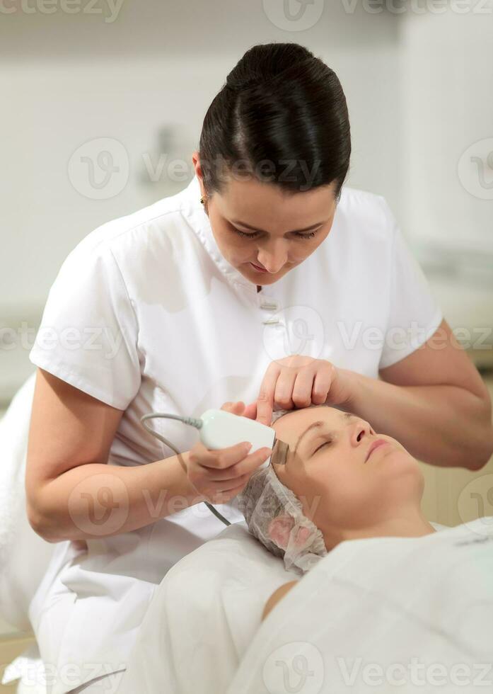 Cosmetician providing ultrasonic facial cleaning photo