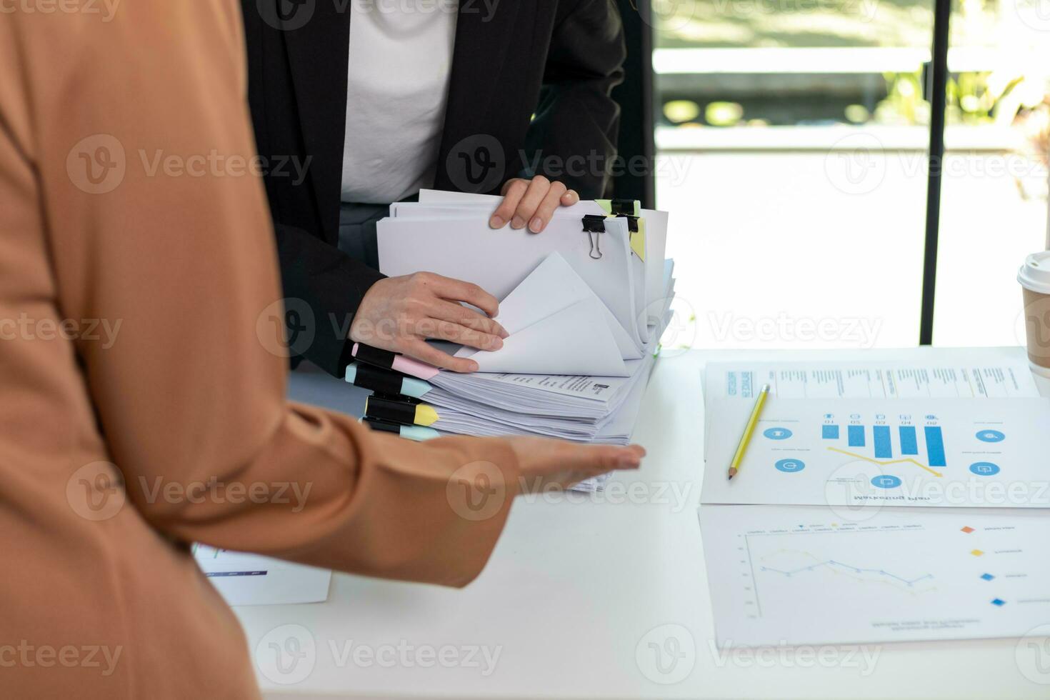 secretary searches through stacked paperwork on desk in office to find lease within stacked paperwork just before meeting. concept difficulty in finding hire purchase contract from stacked paperwork photo