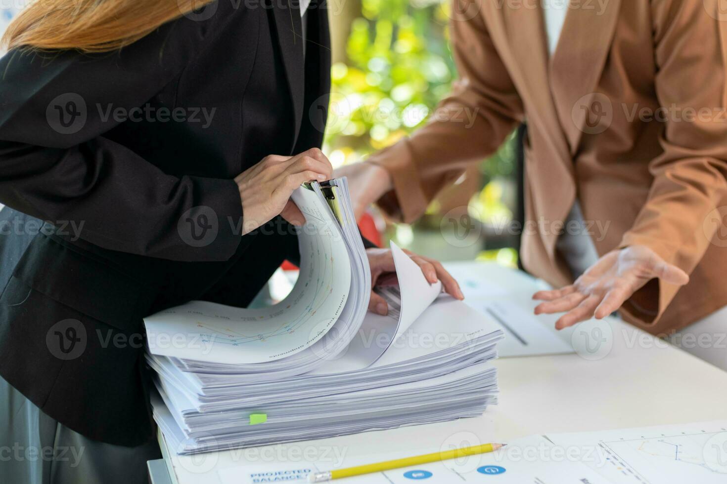 secretary searches through stacked paperwork on desk in office to find lease within stacked paperwork just before meeting. concept difficulty in finding hire purchase contract from stacked paperwork photo