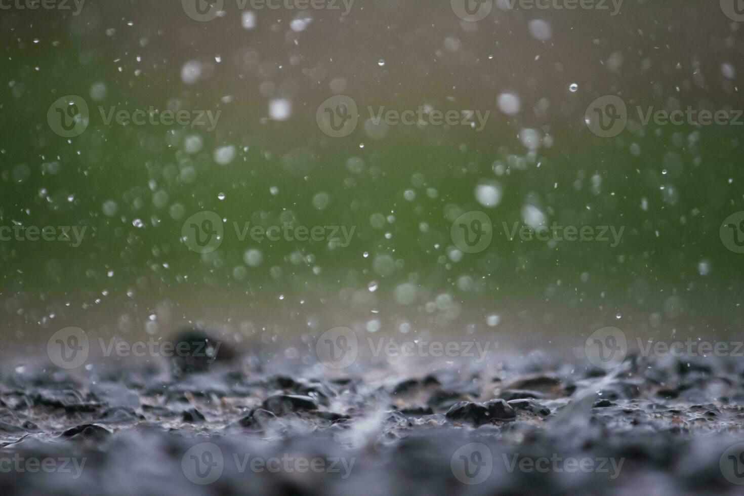 Background of many rain drops falling on the ground due to heavy rain during the rain season causing water splashing from a large number of plots on a blurred background of dark spray. photo