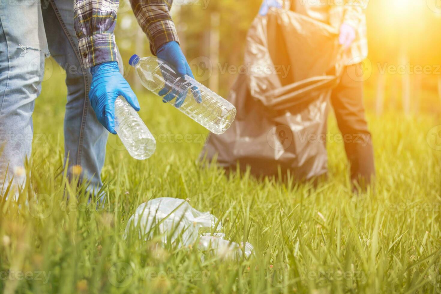 men collect plastic bottles on lawns and walkways in park and put them in bags to help keep them clean They can also collect plastic bottles for recycling. reducing environmental problems by recycling photo
