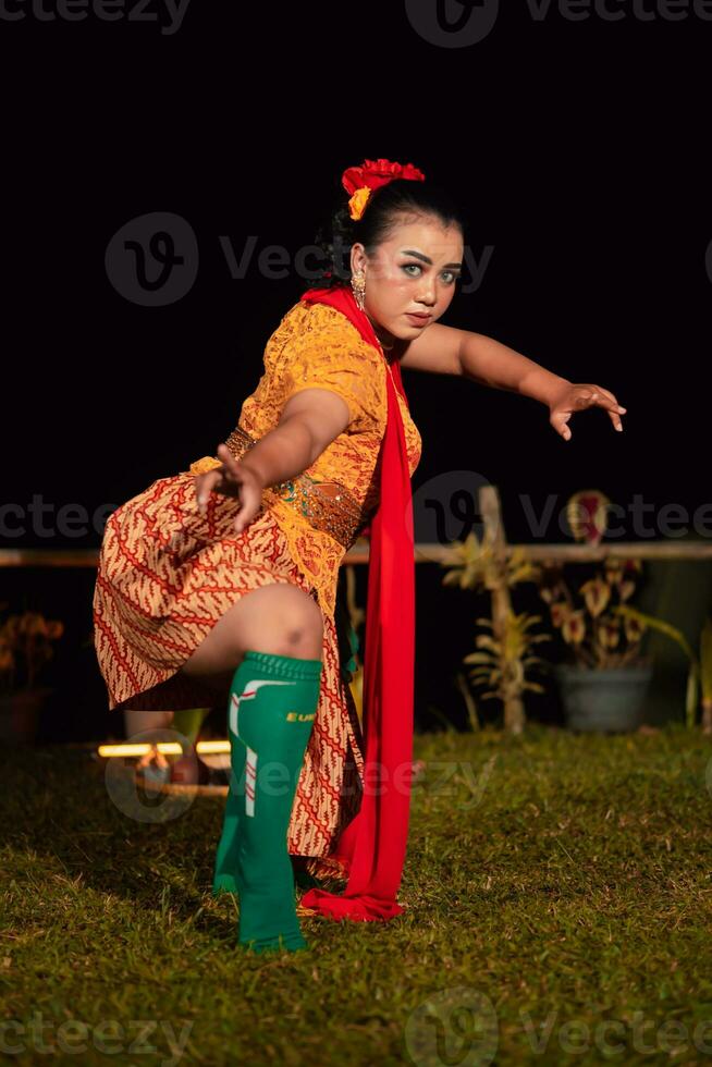 Balinese woman in traditional orange dress dancing with a red scarf while performing dancing photo