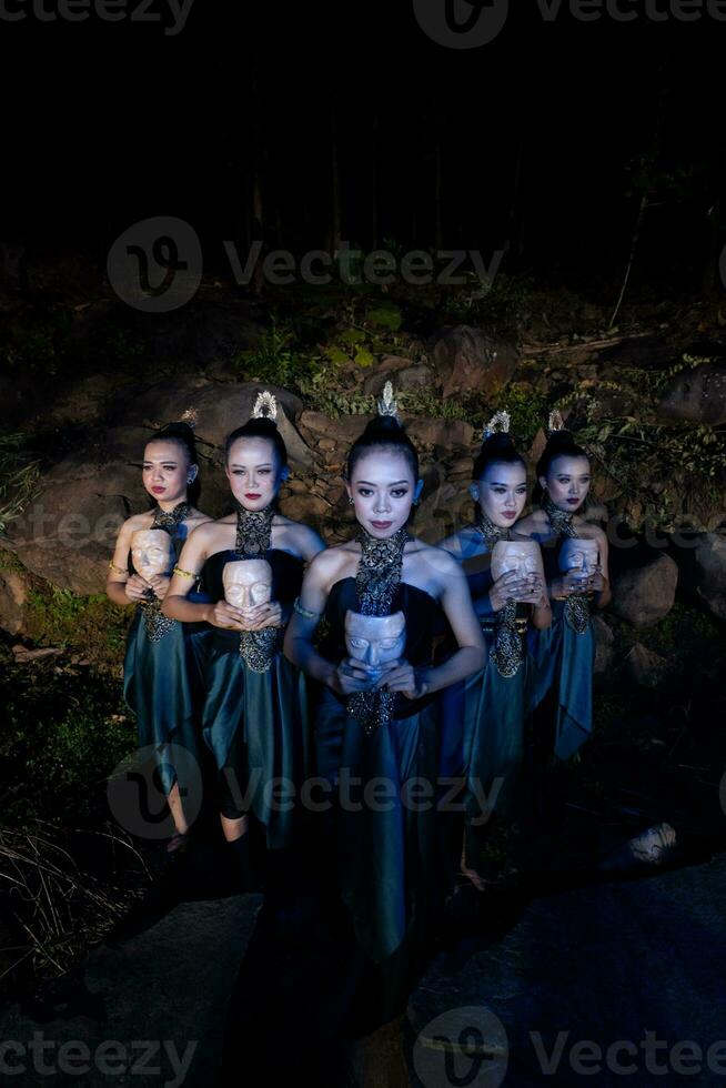 un grupo de mujeres balinesas se alinean con la máscara de madera en sus manos mientras usan trajes de baile tradicionales foto