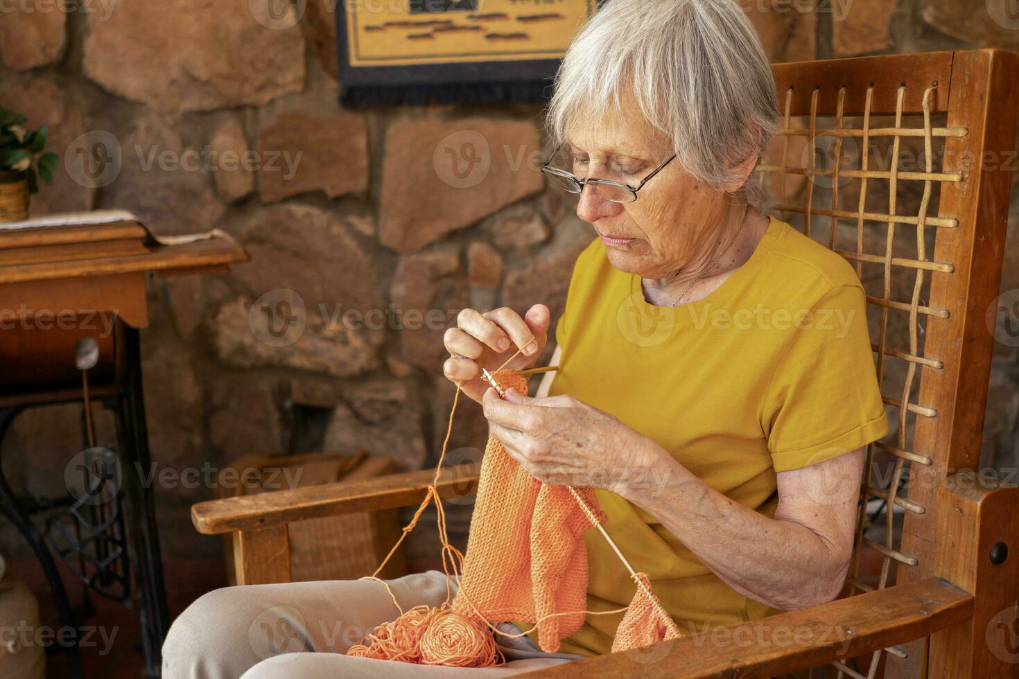 Portrait of an elderly woman knitting at home. photo