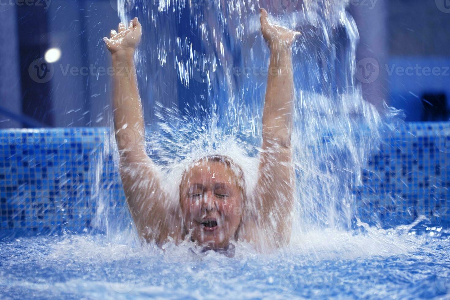 Woman under water stream in the swimming pool photo