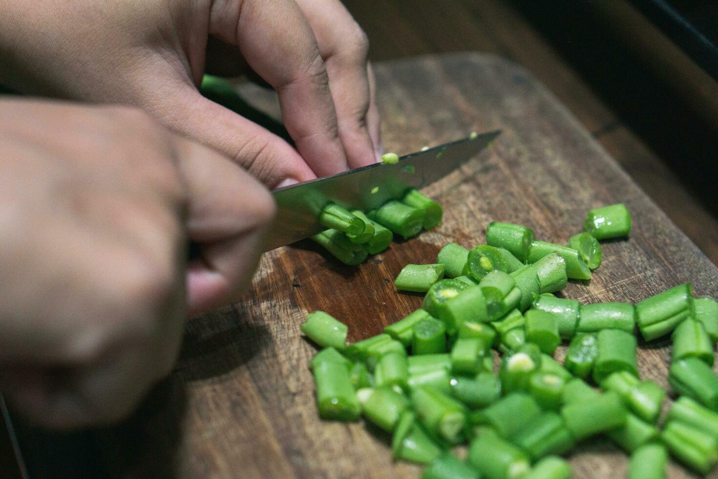 foto de hembra mano el cortar verde frijoles en de madera corte tablero para Cocinando