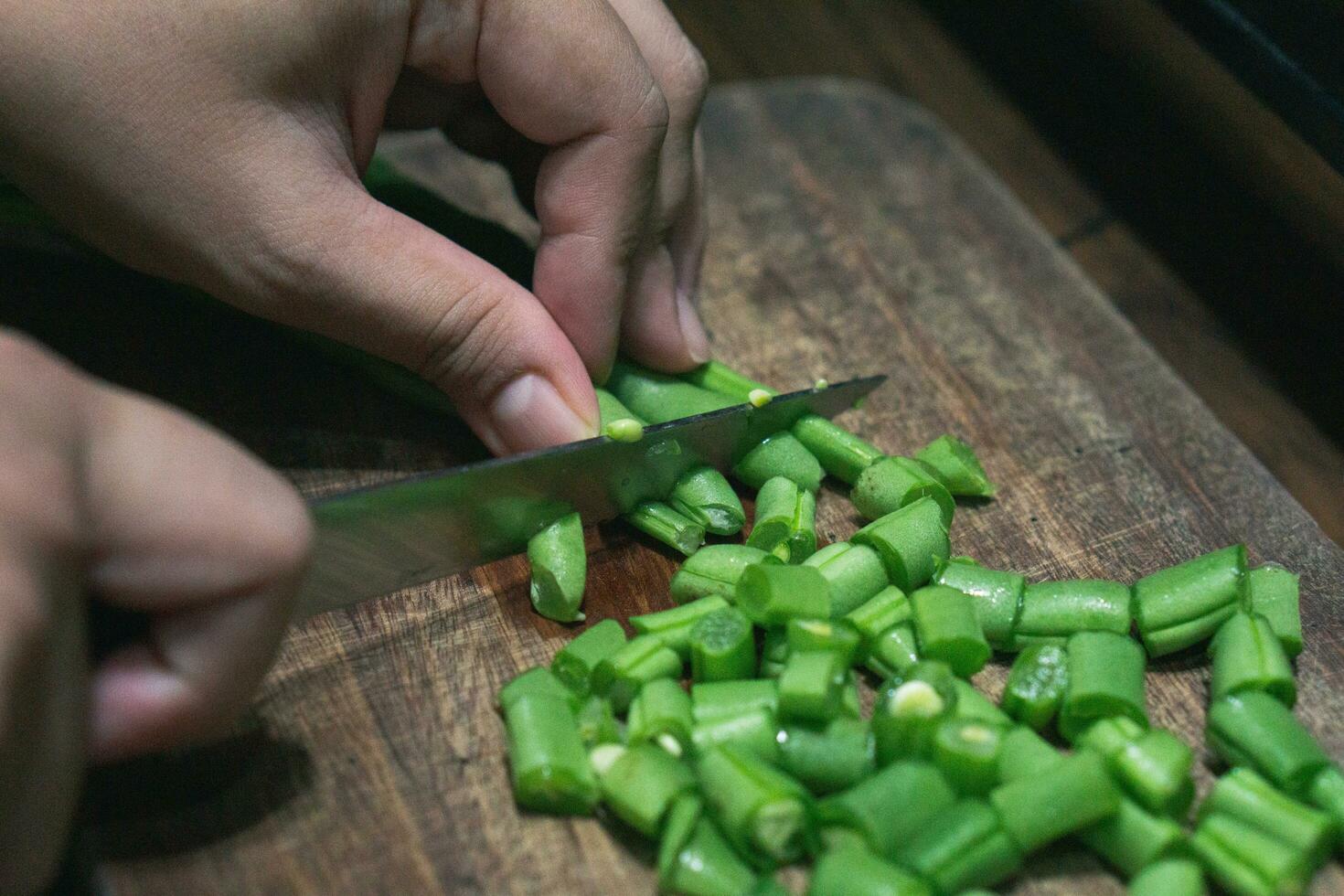 foto de hembra mano el cortar verde frijoles en de madera corte tablero para Cocinando