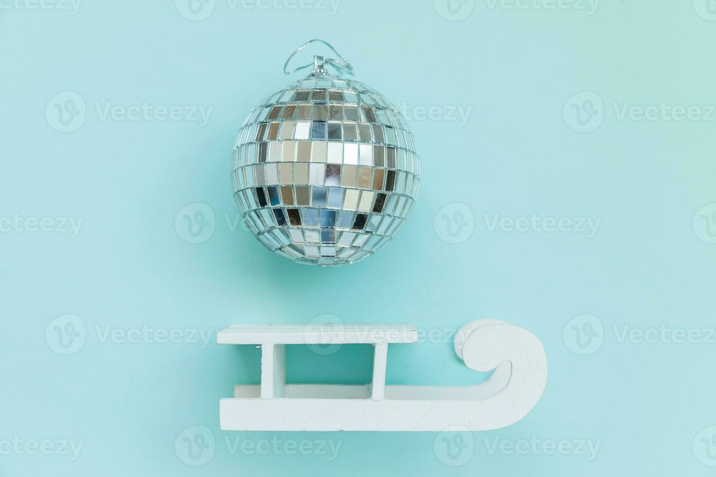 Simply minimal composition winter objects ornament ball sled isolated on blue pastel trendy background photo