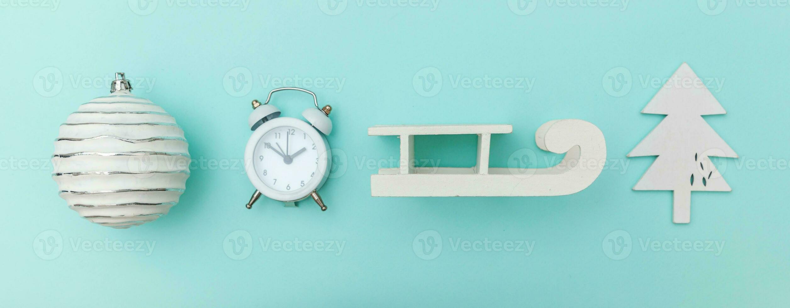 Simply minimal composition winter objects ornament sled fir tree ball alarm clock isolated on blue pastel trendy background photo
