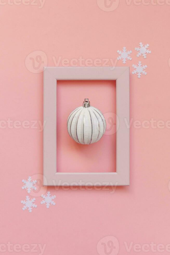 Simply minimal composition winter objects ornament ball in pink frame isolated on pink pastel trendy background photo