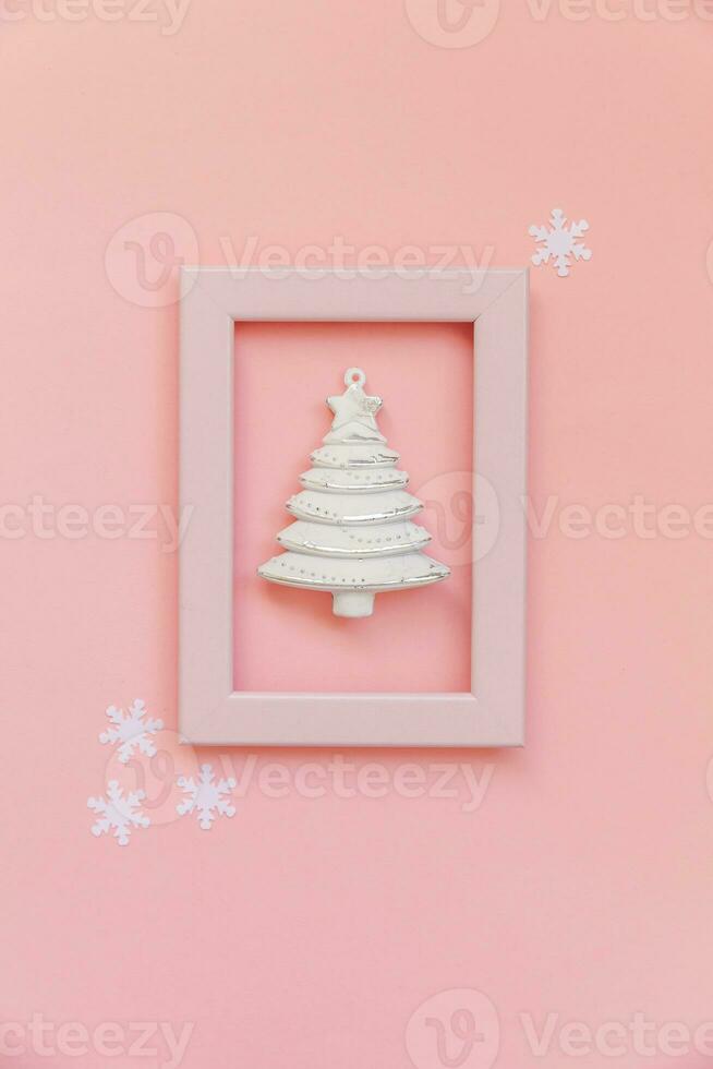 Simply minimal composition winter objects ornament fir tree in pink frame isolated on pink pastel trendy background photo