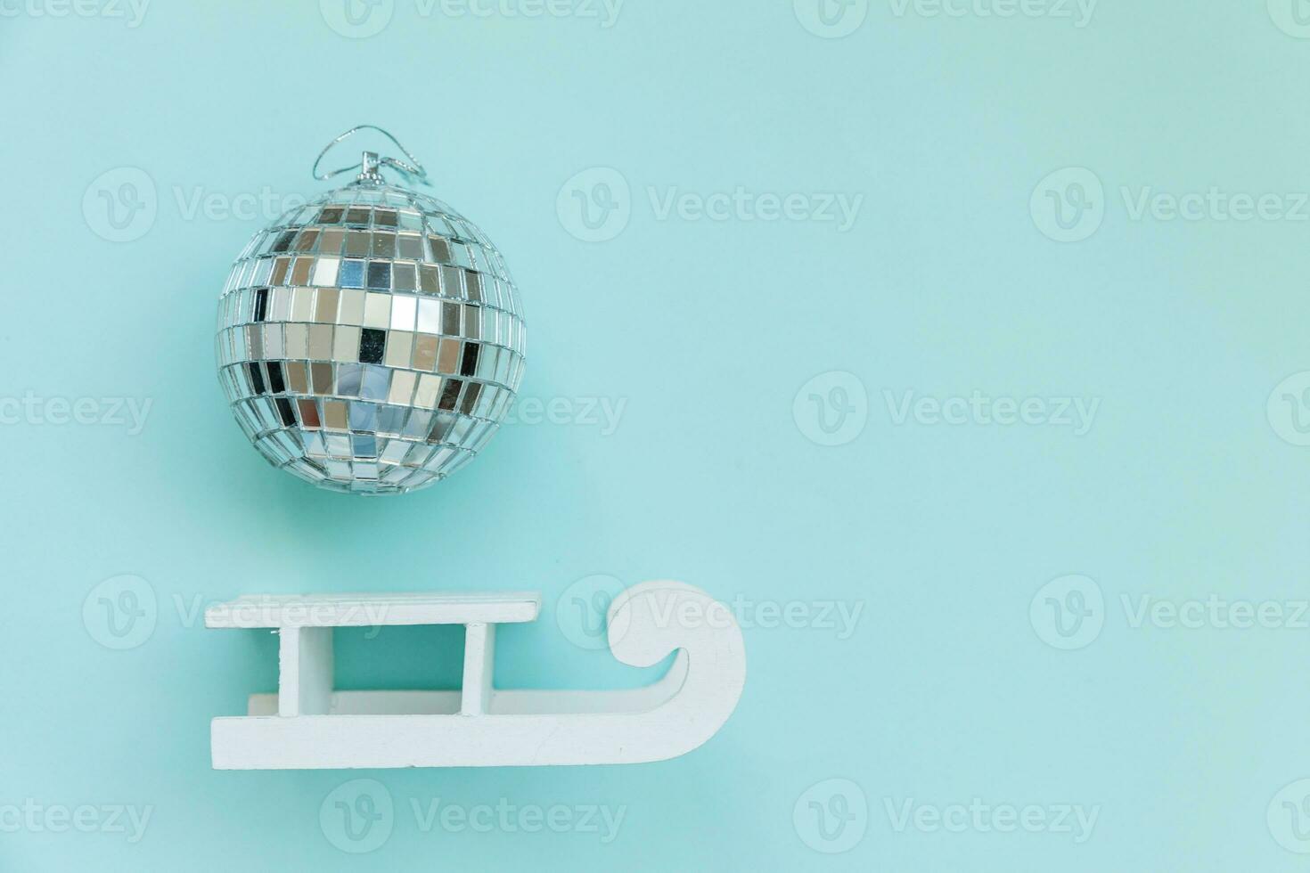 Simply minimal composition winter objects ornament ball sled isolated on blue pastel trendy background photo